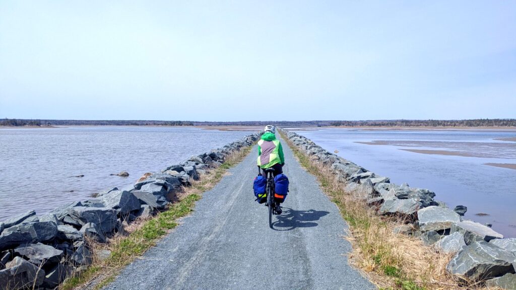 Cyclist riding a bike on a trail with water on both sides
